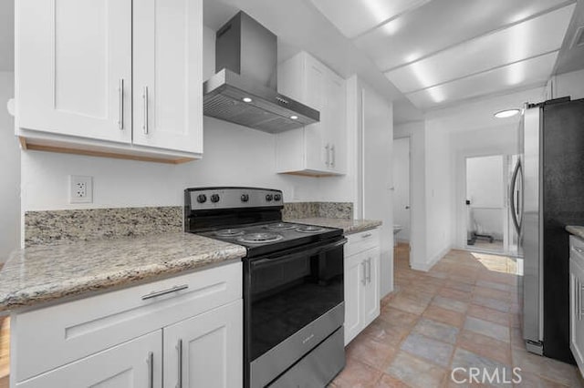 kitchen with light stone counters, electric range oven, stainless steel refrigerator, wall chimney range hood, and white cabinets