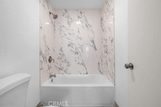 bathroom featuring tub / shower combination and toilet