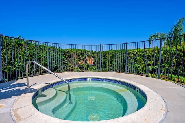 view of swimming pool featuring a community hot tub and fence