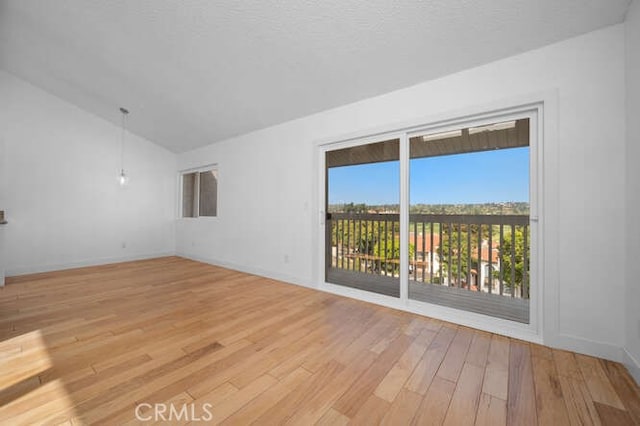 spare room featuring lofted ceiling and light hardwood / wood-style floors