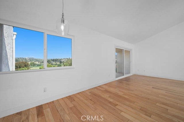 spare room featuring vaulted ceiling and hardwood / wood-style floors