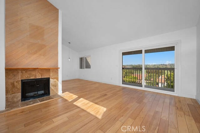 unfurnished living room with hardwood / wood-style flooring, vaulted ceiling, and a tile fireplace