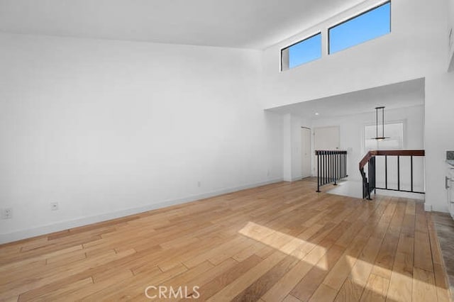 unfurnished living room with light hardwood / wood-style floors and a high ceiling