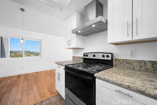 kitchen featuring electric range oven, wall chimney range hood, white cabinets, and decorative light fixtures