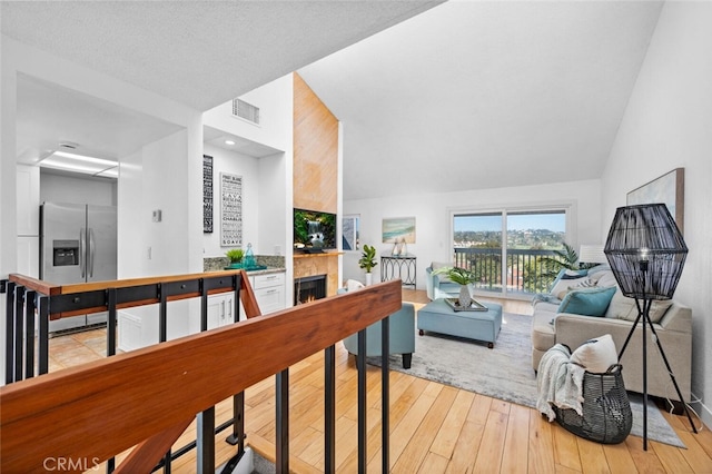 interior space featuring vaulted ceiling, a lit fireplace, light wood finished floors, and visible vents