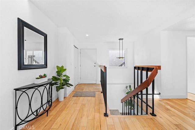 corridor with baseboards, an upstairs landing, and wood finished floors