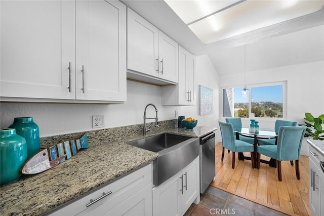 kitchen with light stone counters, decorative light fixtures, stainless steel dishwasher, white cabinets, and a sink