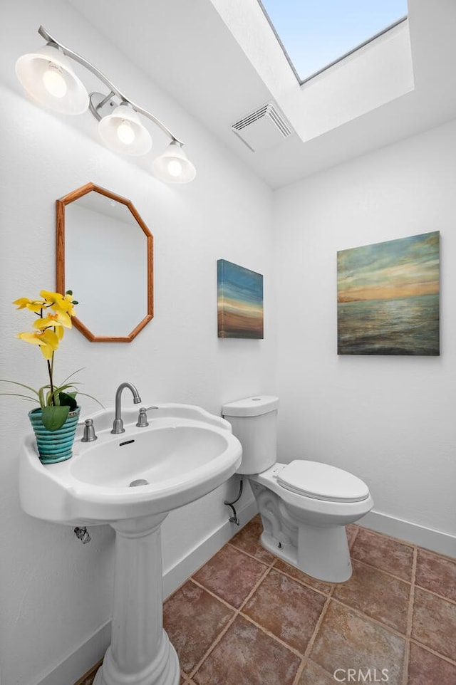 half bath with a skylight, visible vents, toilet, baseboards, and tile patterned floors