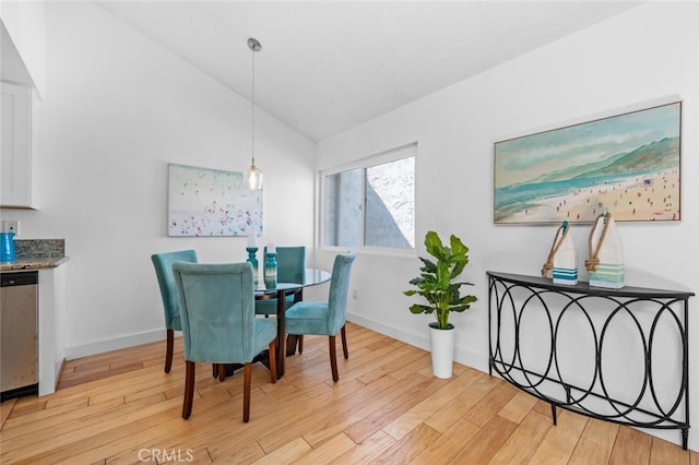 dining room with vaulted ceiling, light wood-type flooring, and baseboards