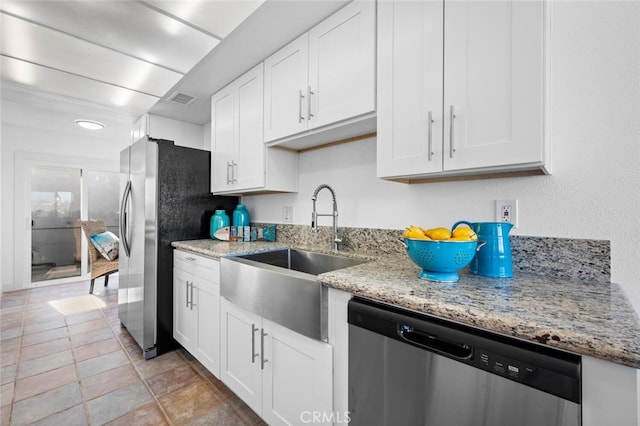 kitchen with appliances with stainless steel finishes, a sink, white cabinetry, and light stone countertops