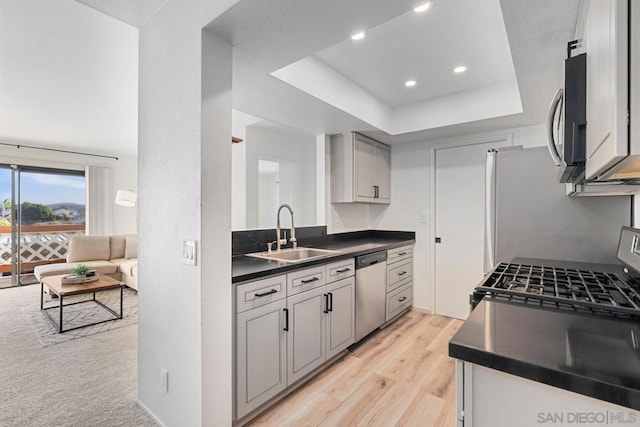 kitchen with sink, a tray ceiling, gray cabinets, and appliances with stainless steel finishes