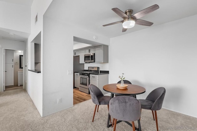 dining space featuring light carpet and ceiling fan