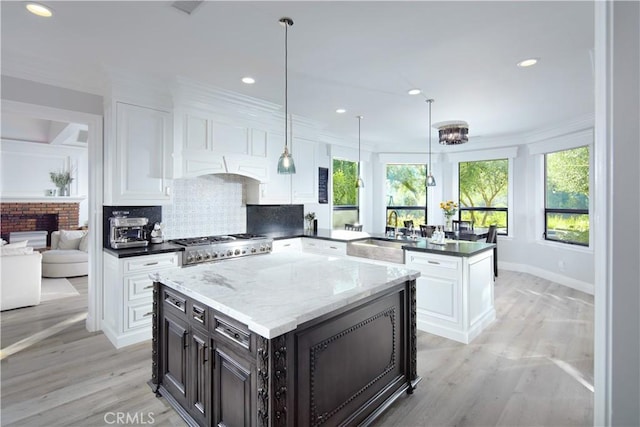 kitchen with hanging light fixtures, a center island, sink, and white cabinets