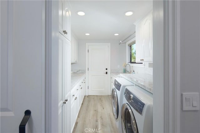 washroom with cabinets, separate washer and dryer, sink, and light wood-type flooring