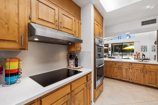 kitchen with black electric stovetop, a skylight, sink, and backsplash