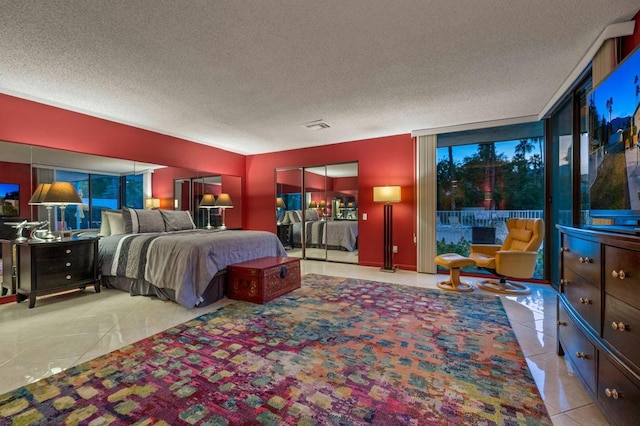 bedroom featuring expansive windows, light tile patterned floors, and a textured ceiling