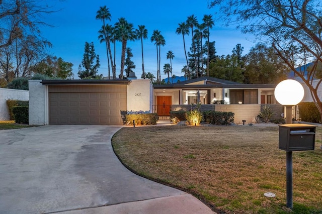 ranch-style house with a garage and a yard