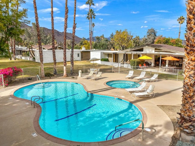 view of pool featuring a hot tub, a mountain view, and a patio