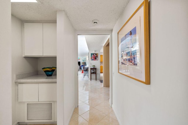 corridor featuring light tile patterned floors and a textured ceiling