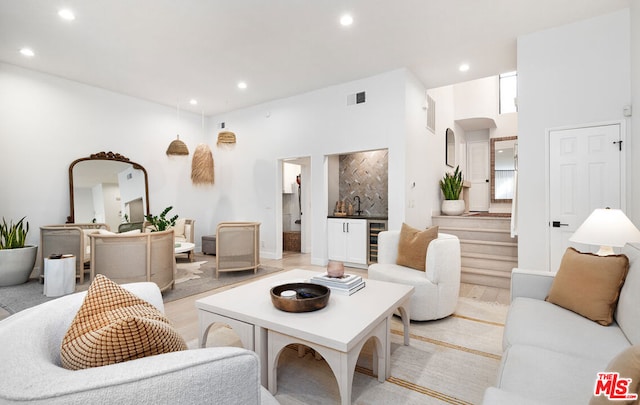 living room featuring a high ceiling, indoor bar, and beverage cooler