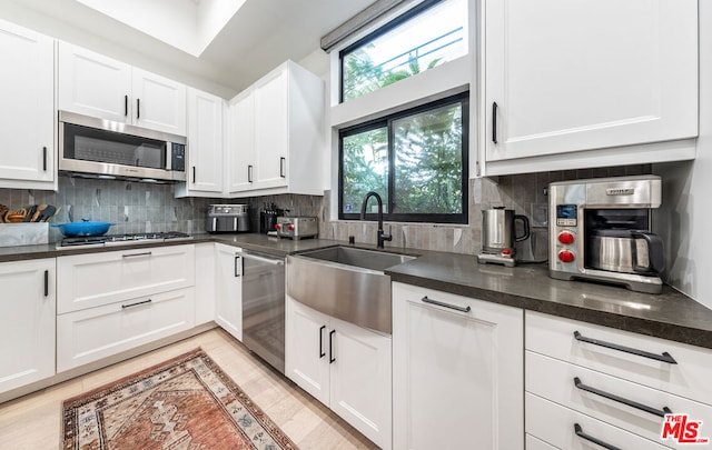 kitchen with white cabinetry, sink, decorative backsplash, and appliances with stainless steel finishes