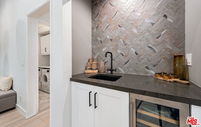 bar with tasteful backsplash, white cabinetry, sink, beverage cooler, and light hardwood / wood-style flooring