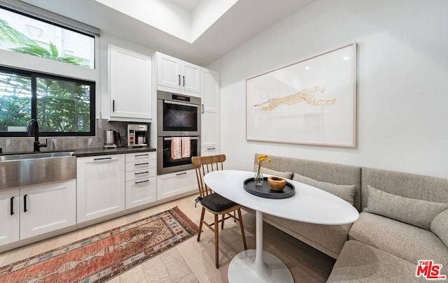 kitchen with tasteful backsplash, white cabinets, double oven, and breakfast area