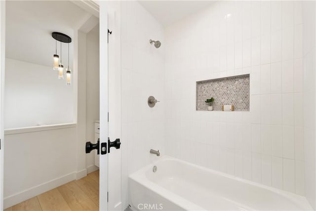 bathroom featuring wood-type flooring and tiled shower / bath