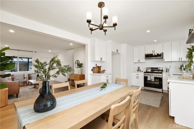 dining space featuring sink, a notable chandelier, and light wood-type flooring