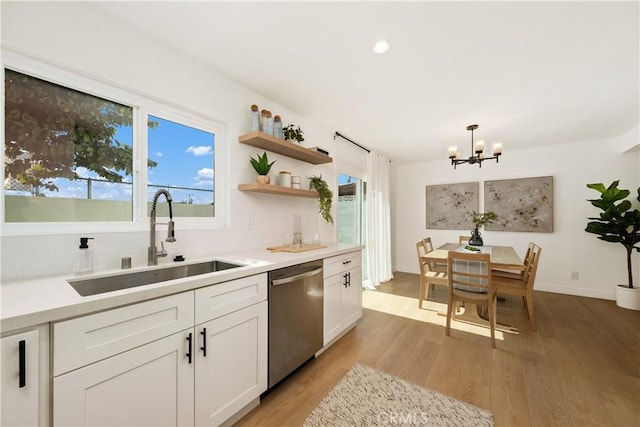 kitchen featuring sink, white cabinetry, decorative light fixtures, light hardwood / wood-style flooring, and dishwasher