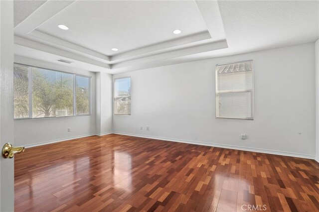 spare room with dark wood-type flooring and a tray ceiling