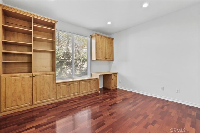 interior space featuring dark wood finished floors, built in desk, recessed lighting, and baseboards