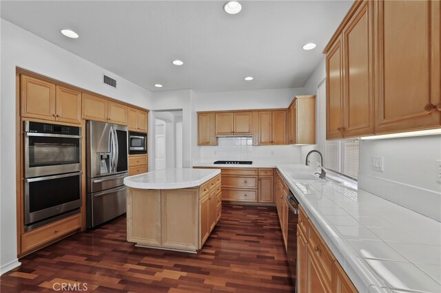 kitchen with a kitchen island, sink, dark hardwood / wood-style flooring, decorative backsplash, and stainless steel appliances