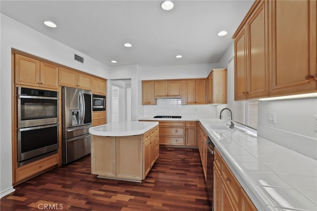 kitchen featuring visible vents, a sink, decorative backsplash, stainless steel appliances, and a center island