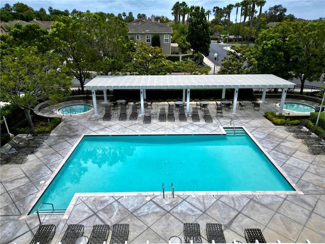 community pool featuring a patio area, a pergola, and a hot tub