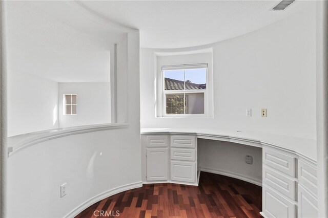 unfurnished office featuring built in desk and dark hardwood / wood-style flooring