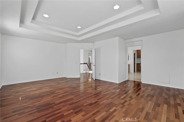 unfurnished living room featuring a raised ceiling and dark hardwood / wood-style floors