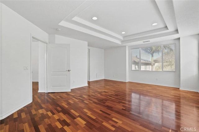 spare room with visible vents, a tray ceiling, wood finished floors, recessed lighting, and baseboards