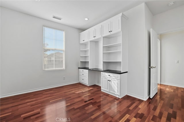 interior space with visible vents, baseboards, dark wood finished floors, and built in study area