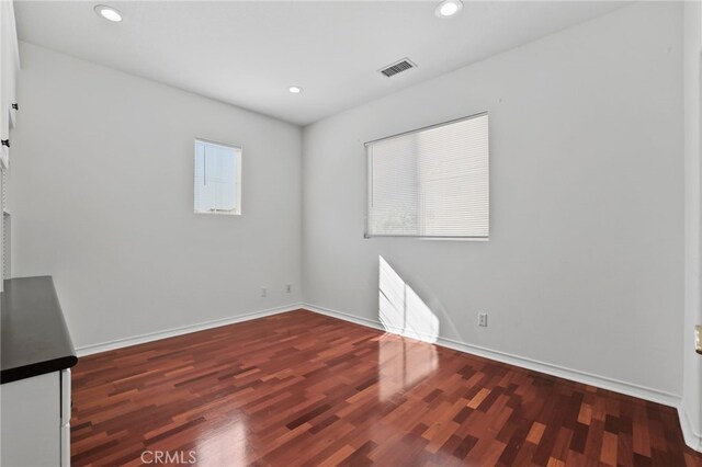 unfurnished room featuring plenty of natural light and dark hardwood / wood-style flooring