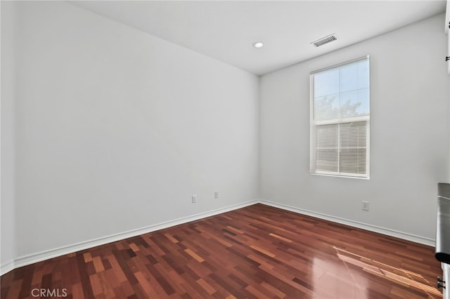 empty room with visible vents, recessed lighting, baseboards, and wood finished floors