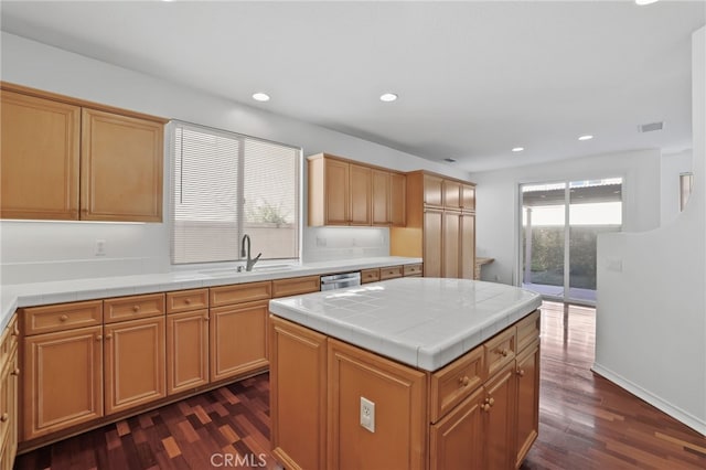 kitchen featuring a kitchen island, dark hardwood / wood-style floors, dishwasher, sink, and tile counters