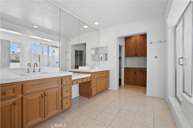 bathroom with an enclosed shower, vanity, tile patterned floors, and a textured ceiling