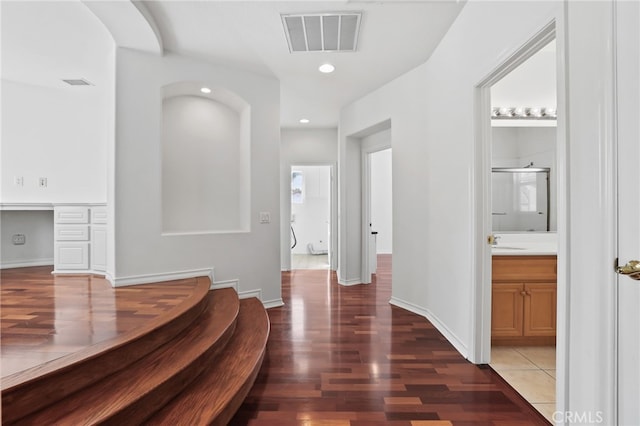 corridor with visible vents, a sink, wood finished floors, recessed lighting, and baseboards