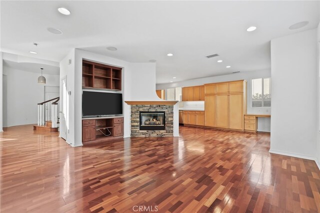 unfurnished living room featuring built in features, visible vents, wood finished floors, and a fireplace