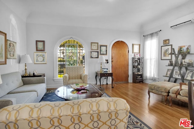 living room with hardwood / wood-style floors, an AC wall unit, and a healthy amount of sunlight