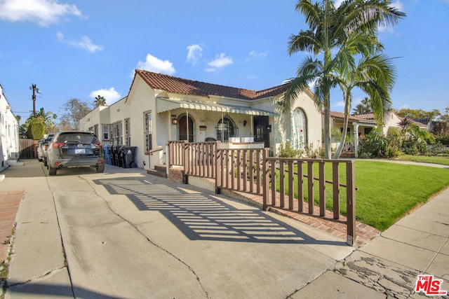 mediterranean / spanish-style house featuring a front lawn and covered porch