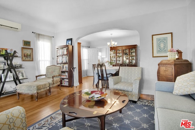 living room with hardwood / wood-style flooring, a wall mounted AC, and a notable chandelier