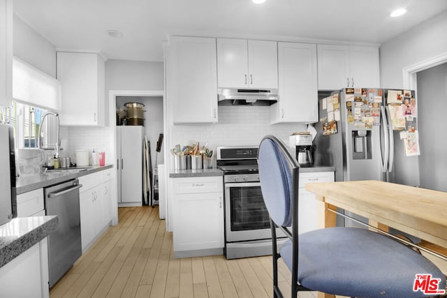 kitchen featuring sink, stainless steel appliances, white cabinets, decorative backsplash, and light wood-type flooring