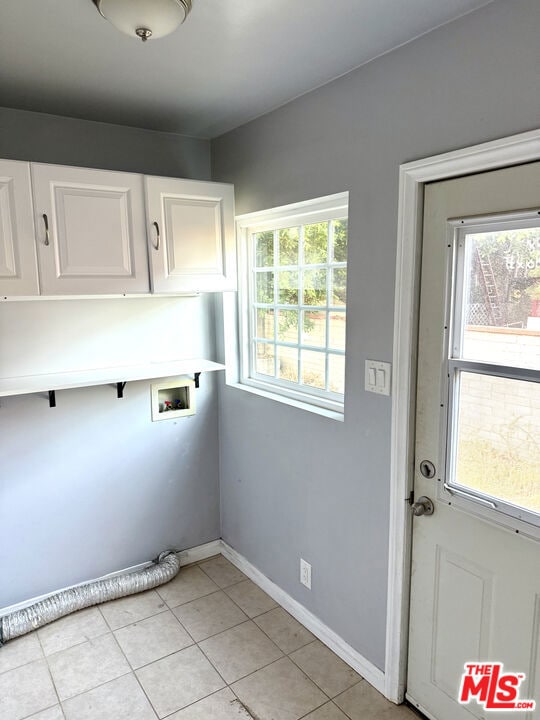 laundry area featuring hookup for a washing machine, a wealth of natural light, cabinets, and light tile patterned flooring